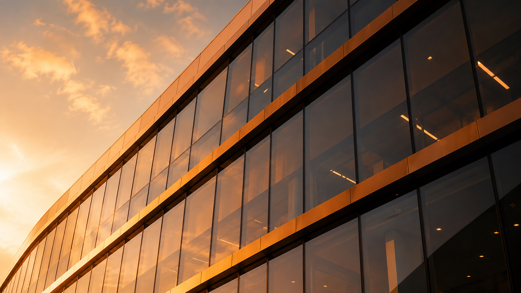 The curved glass façade of a commercial building in warm evening light.